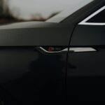 Low-angled close-up of a car's side emblem, capturing sleek design in low light.