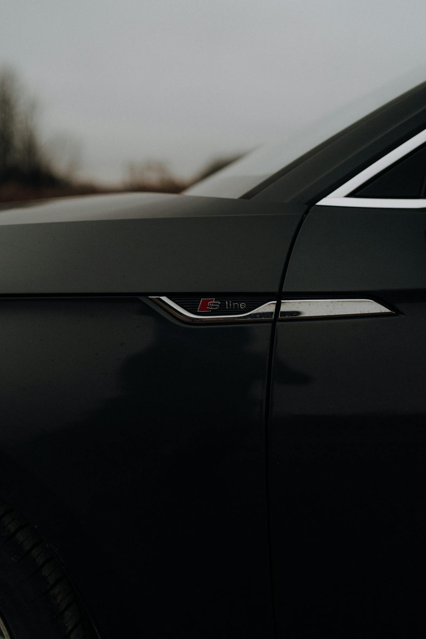 Low-angled close-up of a car's side emblem, capturing sleek design in low light.