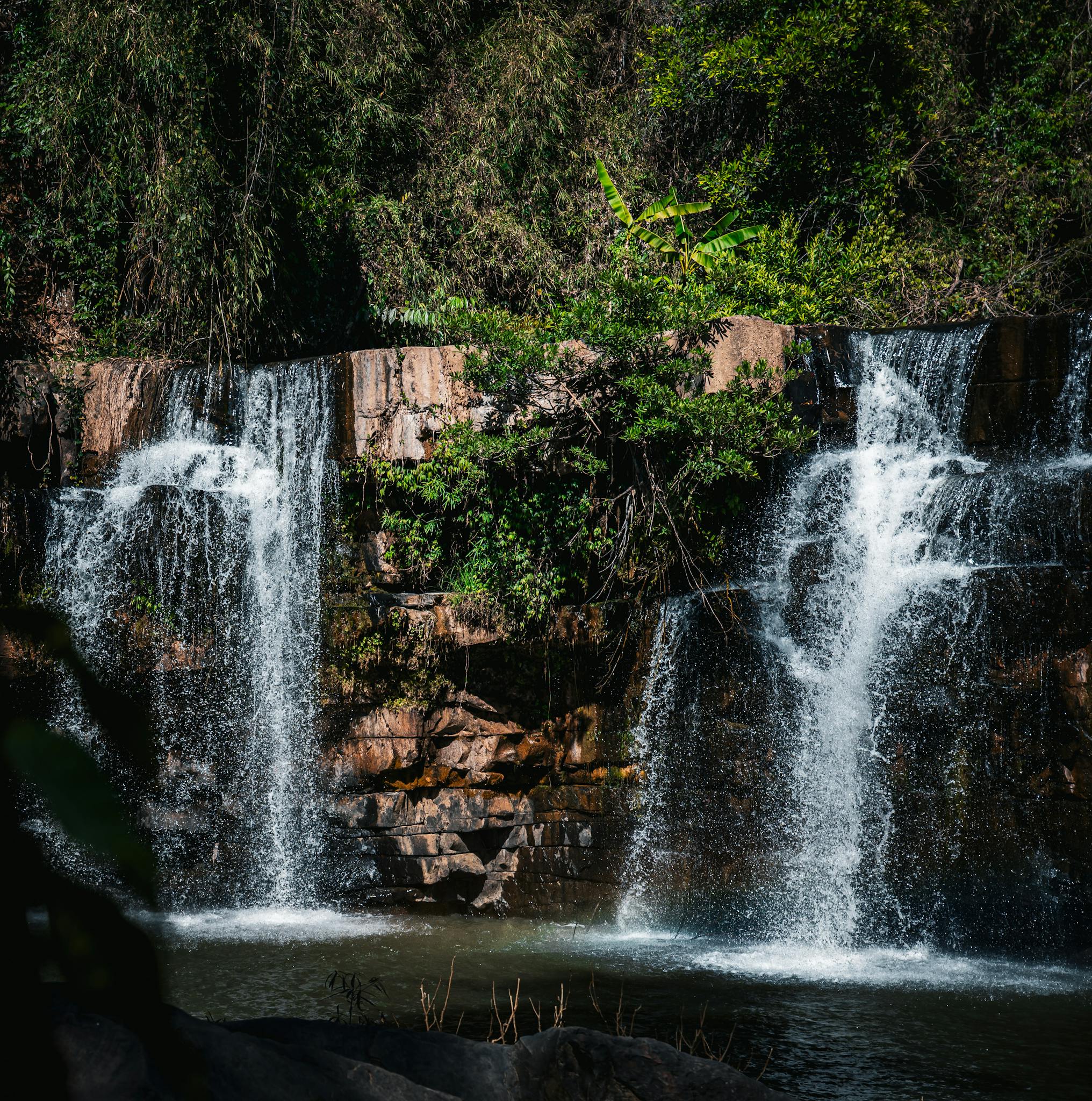 Stunning view of cascading waterfall amidst vibrant greenery in Thailand.